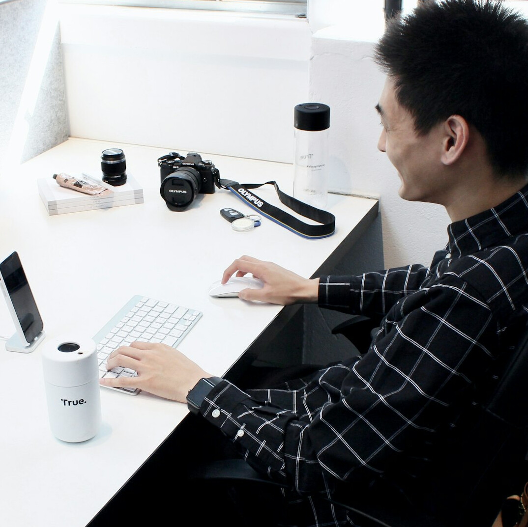 Top view of hands typing on a laptop on a wooden desk with a notebook